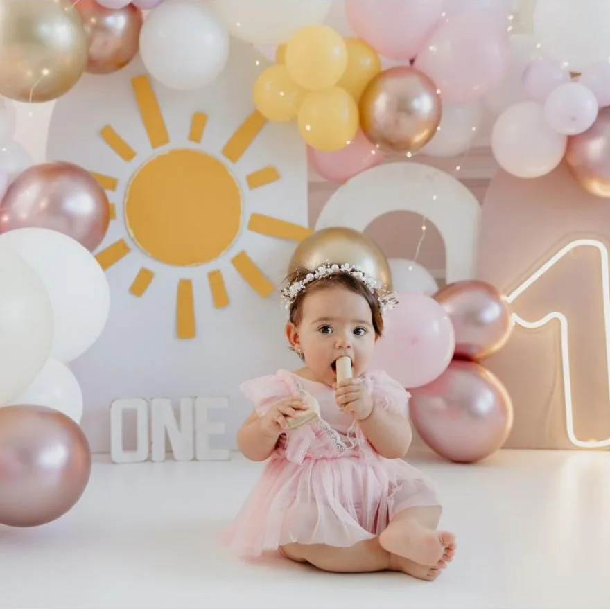 Bebê de vestido rosa em ensaio smash com sol e balões